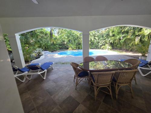 ein Esszimmer mit einem Tisch, Stühlen und einem Pool in der Unterkunft Win Villa in Sosúa