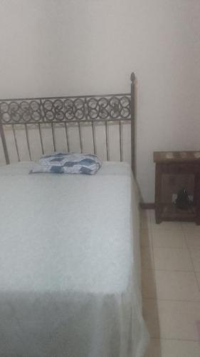 a bedroom with a bed with a pillow and a table at Hospedaria Meu lar 2 in Rio das Ostras