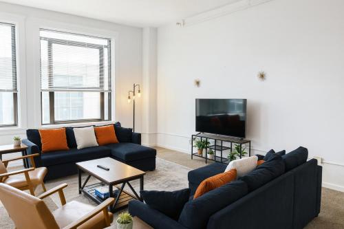 a living room with two blue couches and a tv at Spacious Loft with Fireplace - near CSU, Playhouse, Progressive field, R&R Hall of Fame with Gym & Sauna and Sleeps 12 in Cleveland