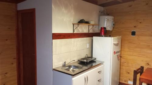 una piccola cucina con lavello e frigorifero di Cabaña El Atardecer 2 a Necochea