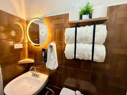 a bathroom with a sink and a mirror and towels at Comod Inn in Manuel F. Martínez