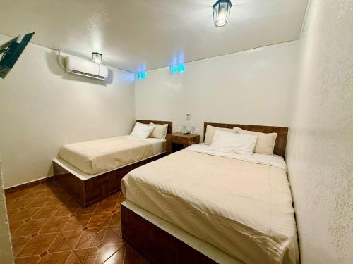 two beds in a small room with blue lights at Comod Inn in Manuel F. Martínez