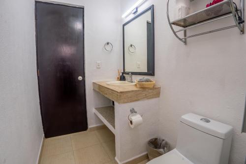 a bathroom with a toilet and a sink and a mirror at Peach35 Apartamento centrico, 5 min de la playa in Cancún