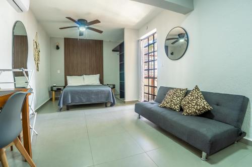 een woonkamer met een bank en een bed bij Peach35L Céntrico studio super ubicado y tranquilo in Cancun