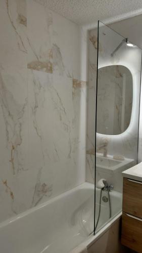 a white bathroom with a tub and a mirror at Front de Neige Isola 2000 in Isola 2000