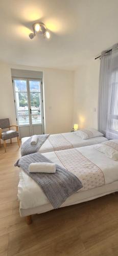 due letti in una camera da letto con finestra di Le Charme du Sanctuaire 8 couchages 400m de la Grotte a Lourdes