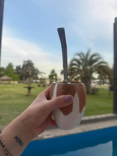 a hand holding a cup with a stick in it at Complejo Bohio Hotel Boutique in Lobos