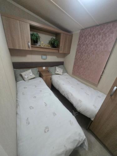 een kleine kamer met twee bedden en een raam bij Leas Happy Haven in Goswick Station