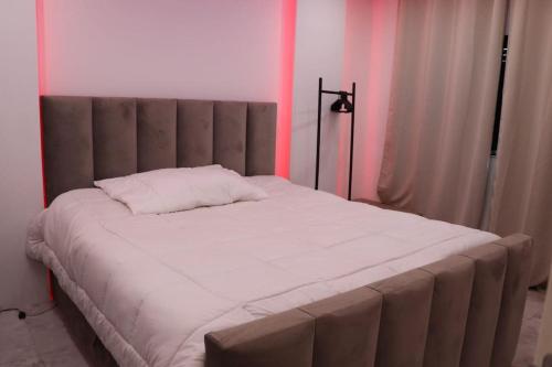 un grande letto in una stanza con illuminazione rosa di Micaya a Praia