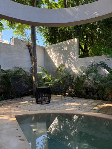 a patio with chairs and a pool of water at Aldea 58, cabañas de lujo con piscina en Merida centro in Azcorra