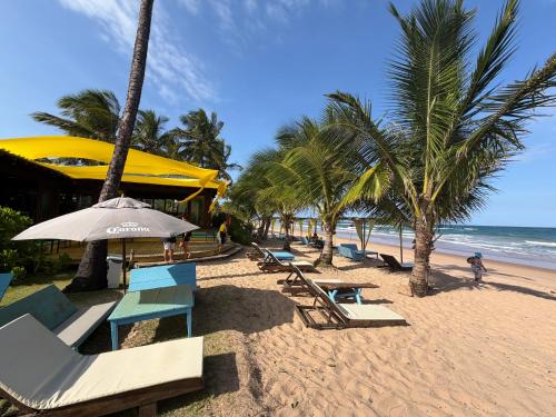 een strand met palmbomen en stoelen en een parasol bij Vila BeiradeiRô - Taipu de Fora in Taipu