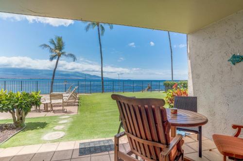 een patio met een tafel en stoelen en uitzicht op de oceaan bij Lauloa 102 in Wailuku
