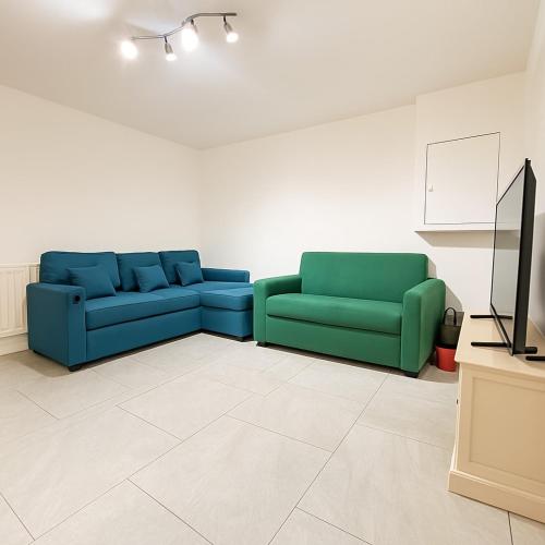 a living room with two blue couches and a tv at The Little Nest Apartment in Manchester