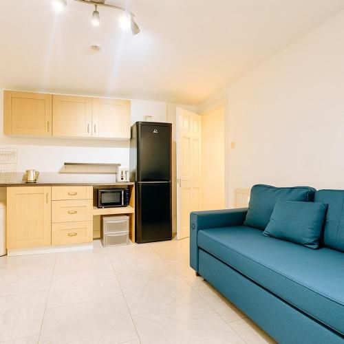 a blue couch in a kitchen with a black refrigerator at The Little Nest Apartment in Manchester