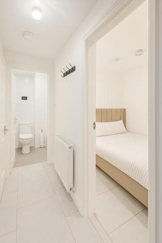 a white bedroom with a bed and a toilet at The Little Nest Apartment in Manchester