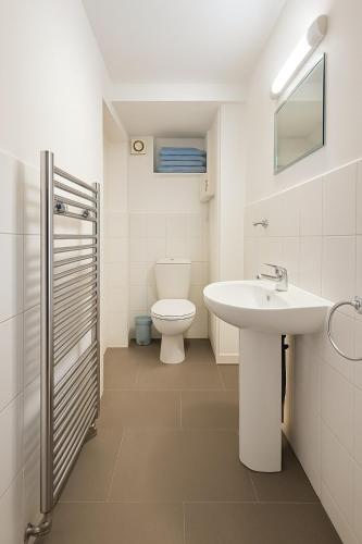 a white bathroom with a sink and a toilet at The Little Nest Apartment in Manchester