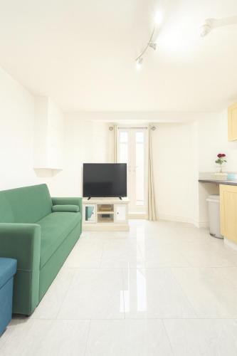 a living room with a green couch and a tv at The Little Nest Apartment in Manchester