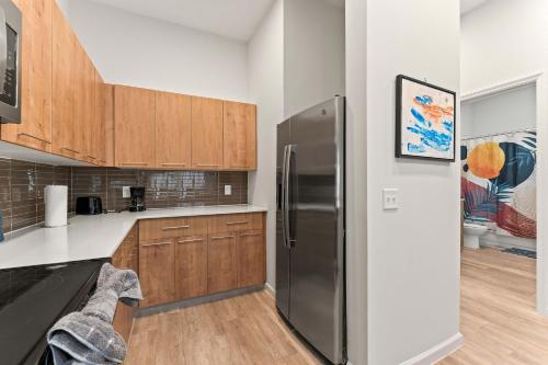 a kitchen with a stainless steel refrigerator and wooden cabinets at Riviere Apartments King Bed Suite & Pool & Gym & Pet Friendly & Near Epic Universe in Orlando