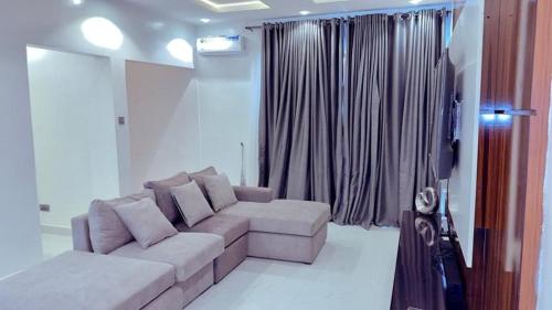 Una sala de estar con un sofá y una ventana. en Gazyhomes1, en Lekki