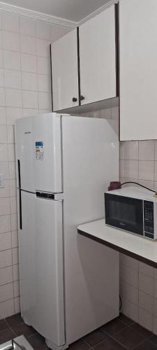 a kitchen with a white refrigerator and a microwave at apartamento 1 quarto in Guarujá