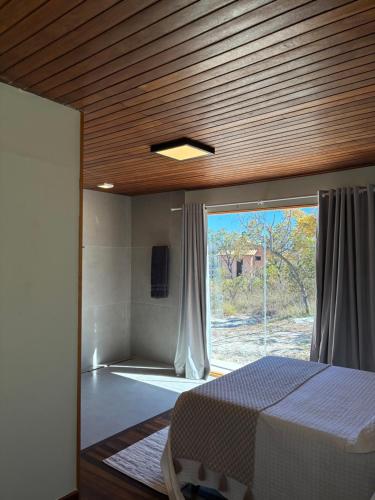 a bedroom with a bed and a large window at Chalé Corumbau - Lapinha da Serra in Santana do Riacho