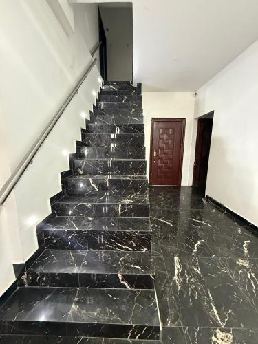 Una escalera con suelo de mármol negro y una puerta marrón. en Jeanael suites, en Manta