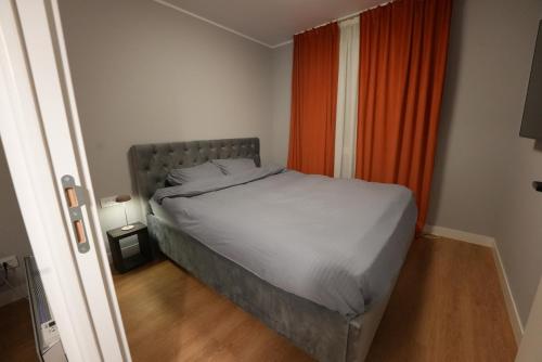 Una cama en un dormitorio pequeño con una cortina naranja. en Alpine Yard Nest Busteni, en Buşteni