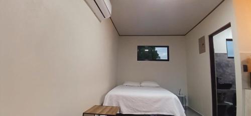 una camera da letto con un letto in una stanza bianca di Apartamentos Jireh a Quepos