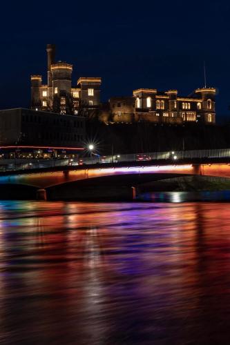 a bridge over a river at night with buildings at River-View Loft, sleeps 4, with parking in Inverness