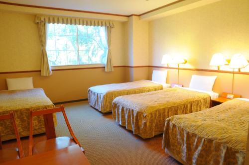 a hotel room with three beds and a window at Atami Hotel Paipuno Kemuri in Atami