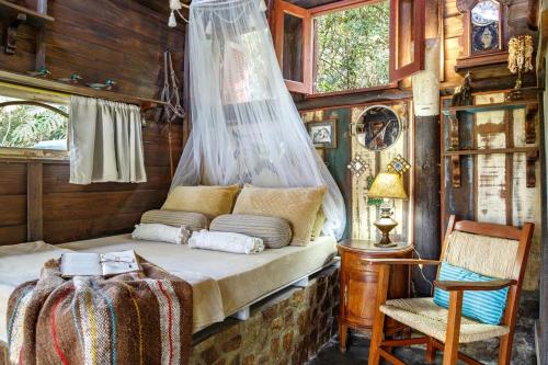 een slaapkamer met een bed en een stoel in een hut bij Pousada DVeras in Garopaba