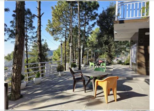 eine Terrasse mit einem Tisch, Stühlen und Bäumen in der Unterkunft Rudrashray Paradise Mussorie in Masuri