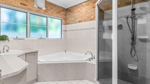 a bathroom with a tub and a sink and a shower at Beachfront Escape in Forster
