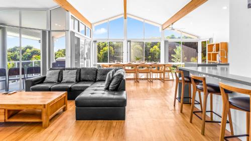 a living room with a black couch and a table at Beachfront Escape in Forster