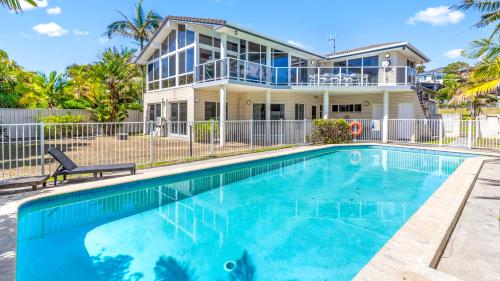 a house with a swimming pool in front of a house at Beachfront Escape in Forster