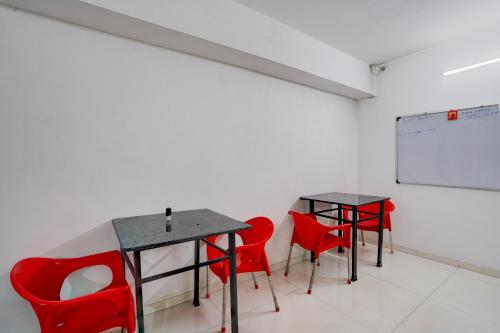 Un aula con dos mesas y sillas rojas y una pared blanca. en Collection O Magarpatta City Formerly Ekab Hospitality, en Mundhwa