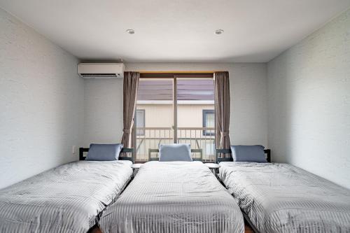 two beds in a room with a window at Prostimo in Bibai
