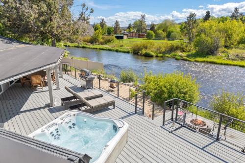 a hot tub on a deck next to a river at Otter Run in Bend