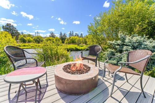 four chairs and a fire pit on a deck with a pond at Otter Run in Bend