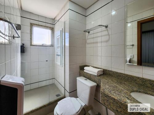 Un baño con inodoro, ducha y lavabo. en Triângulo Apart Hotel, en Vitória
