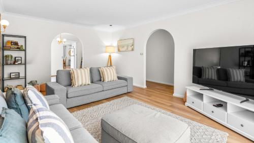 a living room with a couch and a tv at Evergreen Escape in Forster