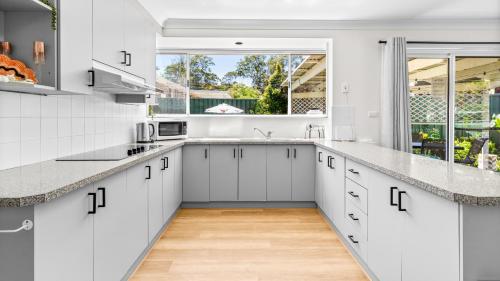 a kitchen with white cabinets and a large window at Evergreen Escape in Forster