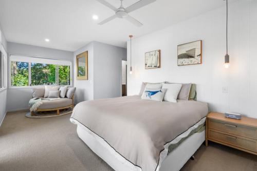 een witte slaapkamer met een groot bed en een stoel bij Golden Valley Luxury Hinterland Escape in Valdora