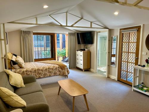 a bedroom with a bed and a couch and a tv at The Cosy Bungalow in Portarlington