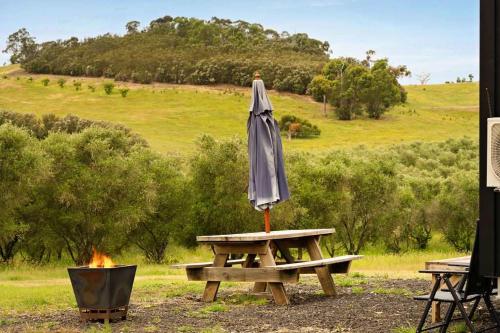 een parasol op een picknicktafel naast een vuur bij Olive Sanctuary by Tiny Away in Taggerty