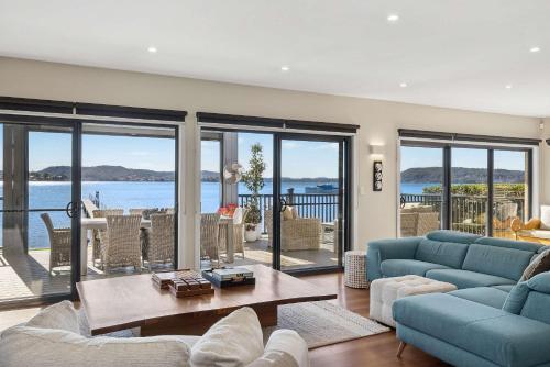 a living room with blue furniture and a view of the ocean at Waters Edge by Coast Hosting in Koolewong