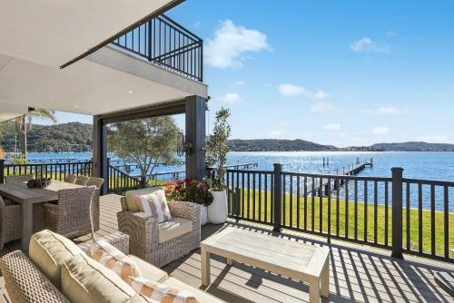 a porch with chairs and a table and the water at Waters Edge by Coast Hosting in Koolewong