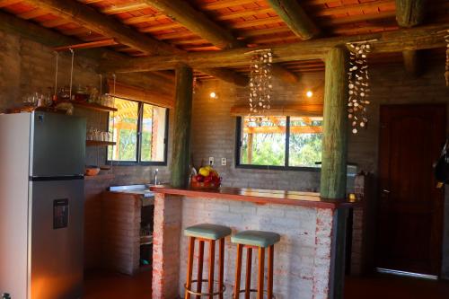 een keuken met een bar met krukken en een koelkast bij Castillito de la viuda casa para 5o 6 personas in Punta Del Diablo