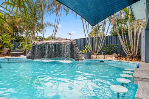 a swimming pool with a waterfall in a yard at Grange Resort Hervey Bay in Hervey Bay