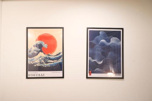 two framed pictures of a tsunami on a wall at ラフィット御徒町 in Tokyo